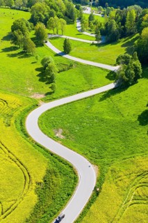 Aerial view of the winding serpentine road between blossoming rapeseed fields from Reifland to