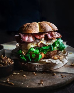 A delicious gourmet burger featuring crispy bacon, fresh lettuce, and melted cheese, perfectly