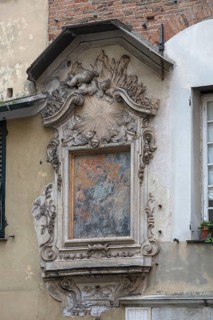Image of a saint with angel figures in the frame on a residential building in the historic centre,