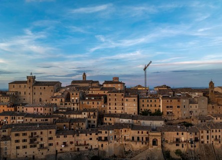 Capture of Treia's historic skyline featuring ancient architecture under a blue evening sky. The