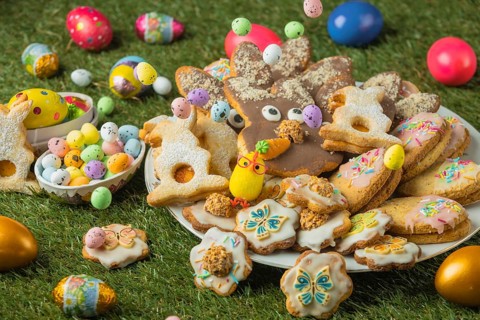 Decorated Easter cookies on a plate with colorful eggs in the grass