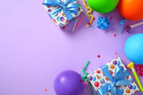 Flat lay, top view of happy birthday purple background with party decorations, gift boxes, balloons