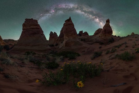 Majestic view of the Utah desert at night with a brilliant Milky Way arch visible above towering