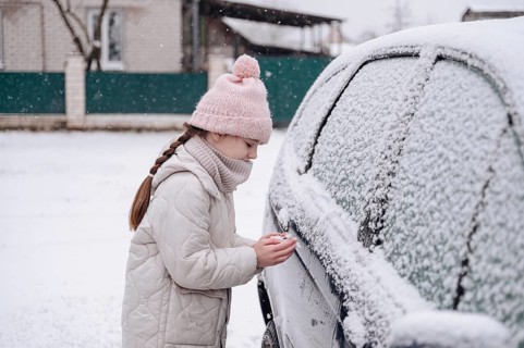 A girl enjoys the snowy January weather in Belarus, dressed warmly in a cozy coat and pink hat,