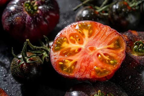 Close up of heirloom tomatoes with a vibrant sliced center, showcasing rich colors and textures.
