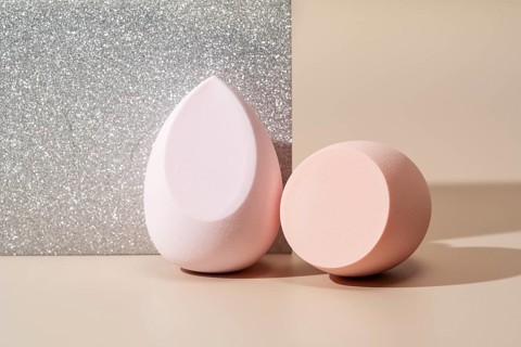 Close-up of two soft cosmetic sponges on a glittery background The round and teardrop-shaped