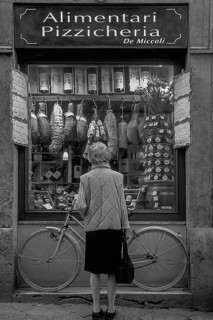 Elderly lady in front of a sausage shop, Siena, Tuscany, Italy