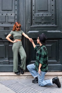 A Colombian lesbian couple shares a romantic moment in front of an elegant dark green door. One