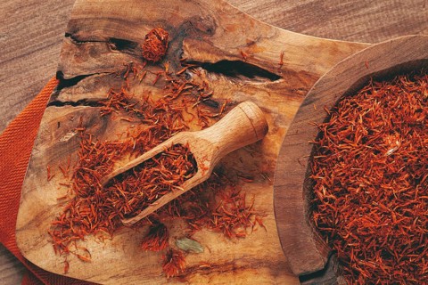 Spice saffron threads, in a wooden bowl, on a wooden table, top view, close-up