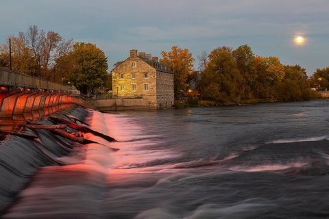 Illuminated Moulin Neuf water flow control dam and walkway over Des Mille-Iles river plus New Mill