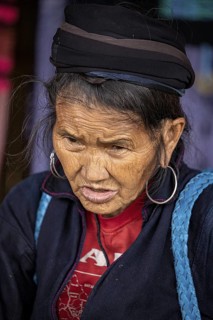 Portrait of an elderly woman in colourful traditional dress with headscarf and large earrings,