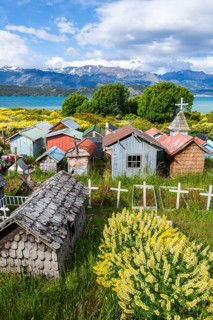 Colourful plastic flowers and graves with miniature houses made of corrugated iron and wooden