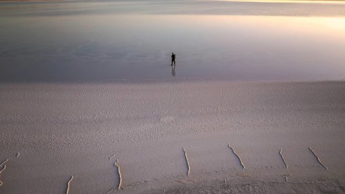 A solitary figure stands on the expansive salt flats of Salinas Grandes, Salta, Argentina,