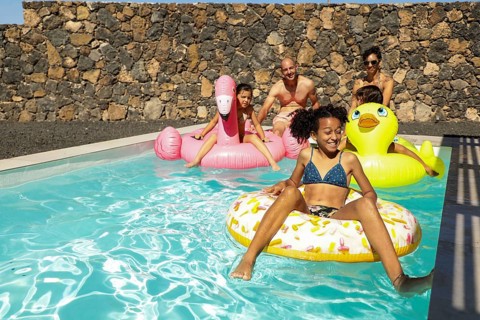A joyful family relaxing in a sparkling pool, surrounded by colorful inflatable floats. Bright