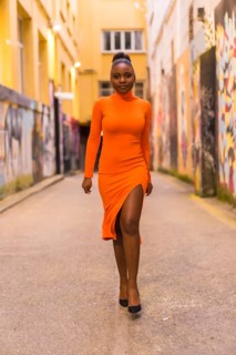 Fashionable urban style with a black African girl in an orange dress and black heels on a city