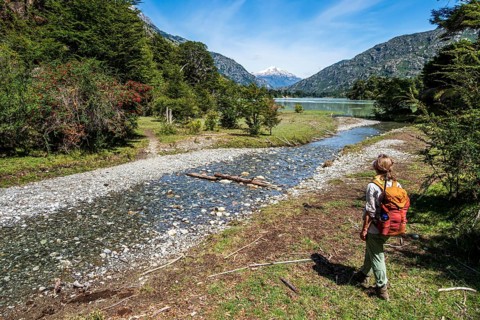 Woman hikes near river Rio Baker (back), trail to historical monument Corte San Carlos, Patagonia,