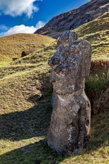 A single moai against a hilly background in sunlight, the moai statues on Easter Island in the