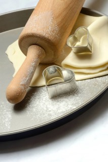 Rolled dough on cake tray with dough rollers and cookie cutters