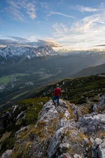 View of Wetterstein mountains with Zugspitze, mountaineer at the summit of Kramerspitz, at sunset,