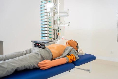 Doll on treatment couch in hospital environment with medical equipment, fire department exercise on