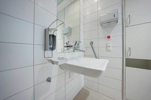 Sterile bathroom with modern sink and tiles in hospital environment, patient room cash desk in the