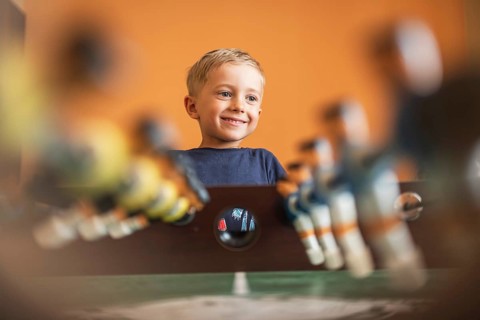 Boy throws the ball on the football table