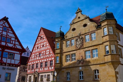 A series of historic half-timbered houses with elaborate architecture under blue skies,