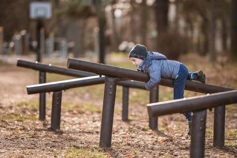Six years old boy exercises at the obstacle course in the park