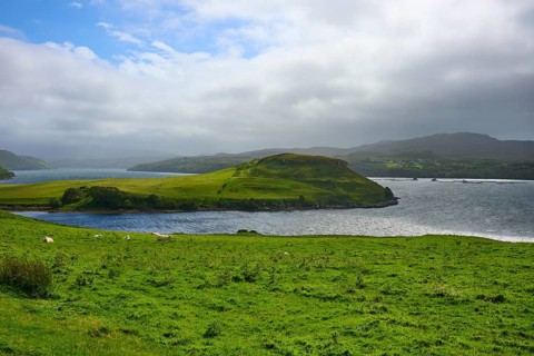 Green island with blue sky and clouds over a calm sea, Isle of Skye, Scotland, United Kingdom,
