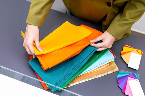 A professional arranges vibrant fabric swatches on a table, focusing on color coordination and