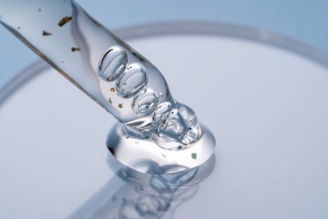 Macro shot of a cosmetic pipette filled with liquid, showcasing air bubbles and minute gold