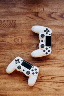 Two white gaming controllers lay on a wooden surface, highlighting sleek design and modern