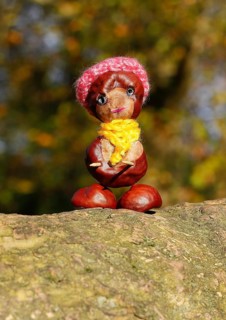 Funny chestnut figure with hat and scarf on a tree trunk, North Rhine-Westphalia, Germany