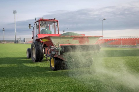 Pouring infill granules in to a football pitch with artificial grass in Lubin, Poland