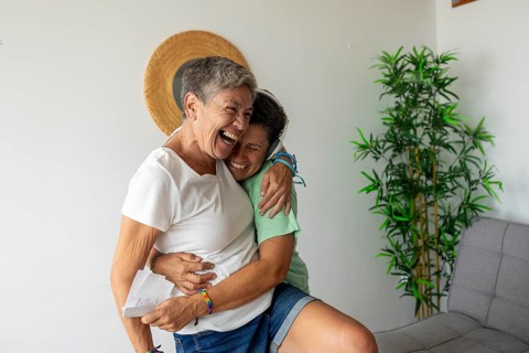 Joyful lesbian couple embracing and laughing as they prepare for their upcoming summer holidays,