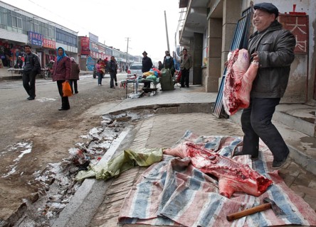 Xining, CHN, 27.02.09 - A butcher cuts up a pork side on the sidewalk of a village near Xining,