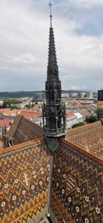 Towering church tower with intricately decorated roof in urban surroundings, Slovakia