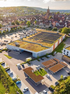 Aerial view of a town with a large building with solar panels installed on its roof, a car park and