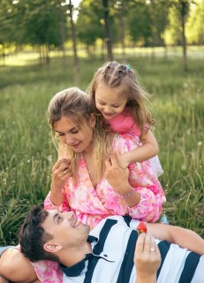Young parents with their little daughter on a picnic in the park in summer. Family time together