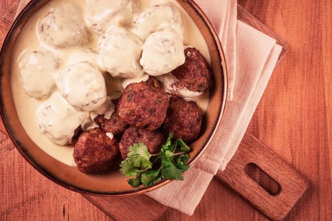 Swedish meatballs in cream sauce, plate on a wooden table, homemade, no people