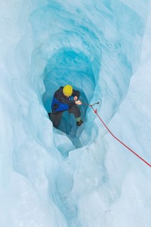 Mountaineer moving up ice cave, Fox Glacier, Westland National Park, South Island, New Zealand