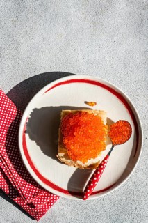 From above, a vibrant dish of healthy organic red caviar from trout fish is served on a toasted