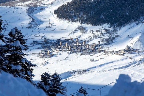 A picturesque village nestled in a snow-covered valley, featuring ancient watchtowers amid a