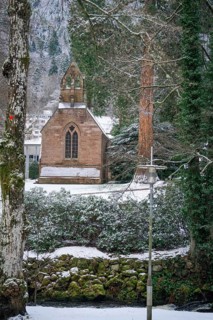 Snowy chapel in the forest, surrounded by trees, with a quiet winter atmosphere, spa garden,