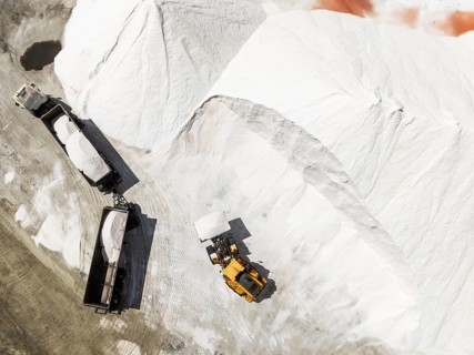 Lorry and excavator at the salt heaps of the Walvis Bay Salt works. Aerial view. Drone shot. Walvis