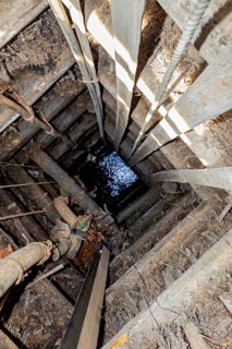 View of a deep wooden well with water at the bottom, the sapphire and gemstone mines at Ratnapura