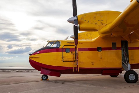 A vibrant yellow Bombardier aircraft on the runway at Torrejon Air Base, Spain. The plane is ready