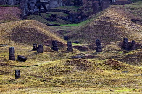 Several moai on a wavy hilly landscape under a cloudy sky, the moai statues on Easter Island in the
