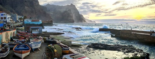 Sunset over a coastal landscape with colorful fishing boats and mountains, romantic harbor scene,