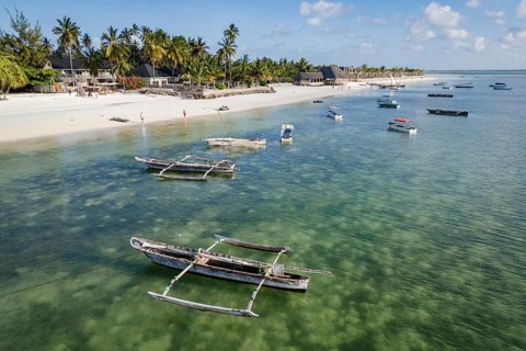 Aerial view of traditional wooden boats anchored in clear turquoise water along a tropical white